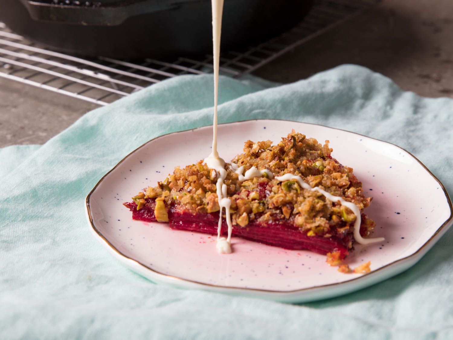 Closeup of a slice of the beet gratin being drizzled with crème fraîche.