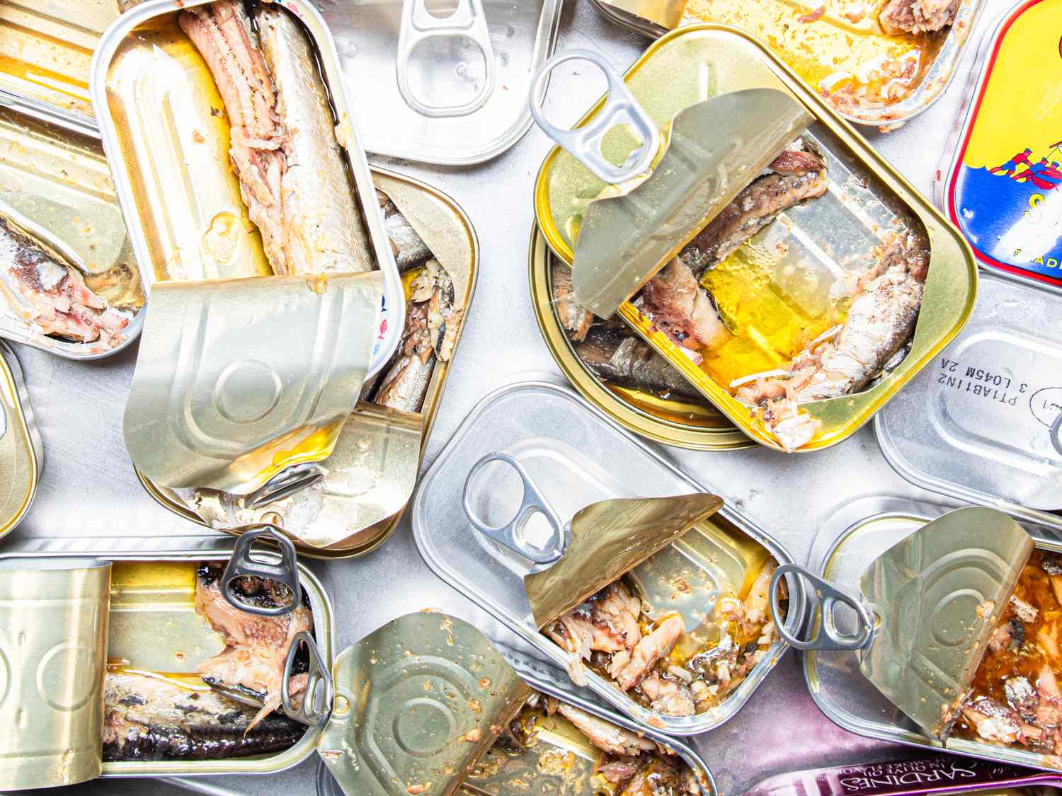 Opened sardine cans scattered on a surface showing their contents of fish