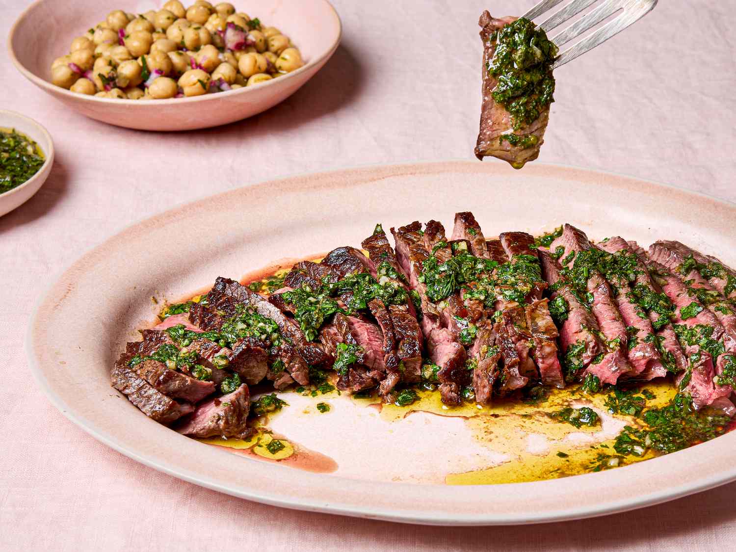 Sliced steak topped with green chermoula served with chickpea salad on the side