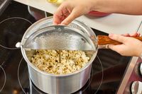 A person lifts up the lid on the Wabash Valley Farms Original Whirley-Pop Popcorn Popper Stainless Steel