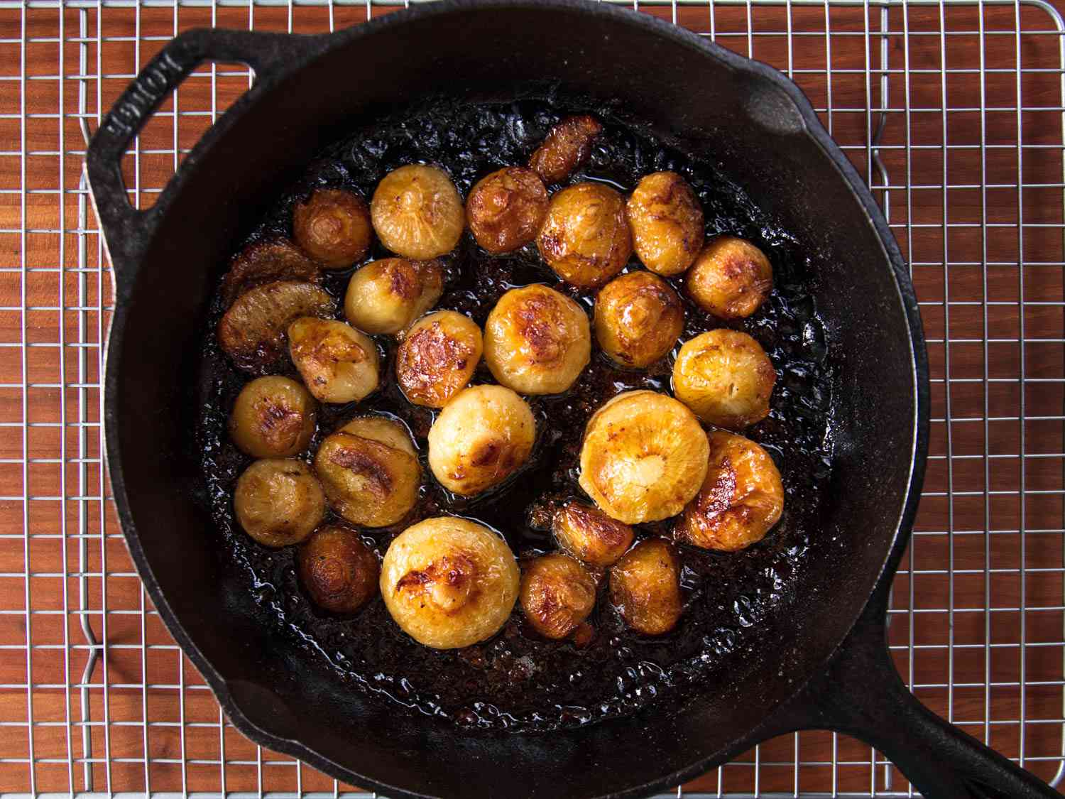 Whole roasted cipollini onions in a cast iron skillet