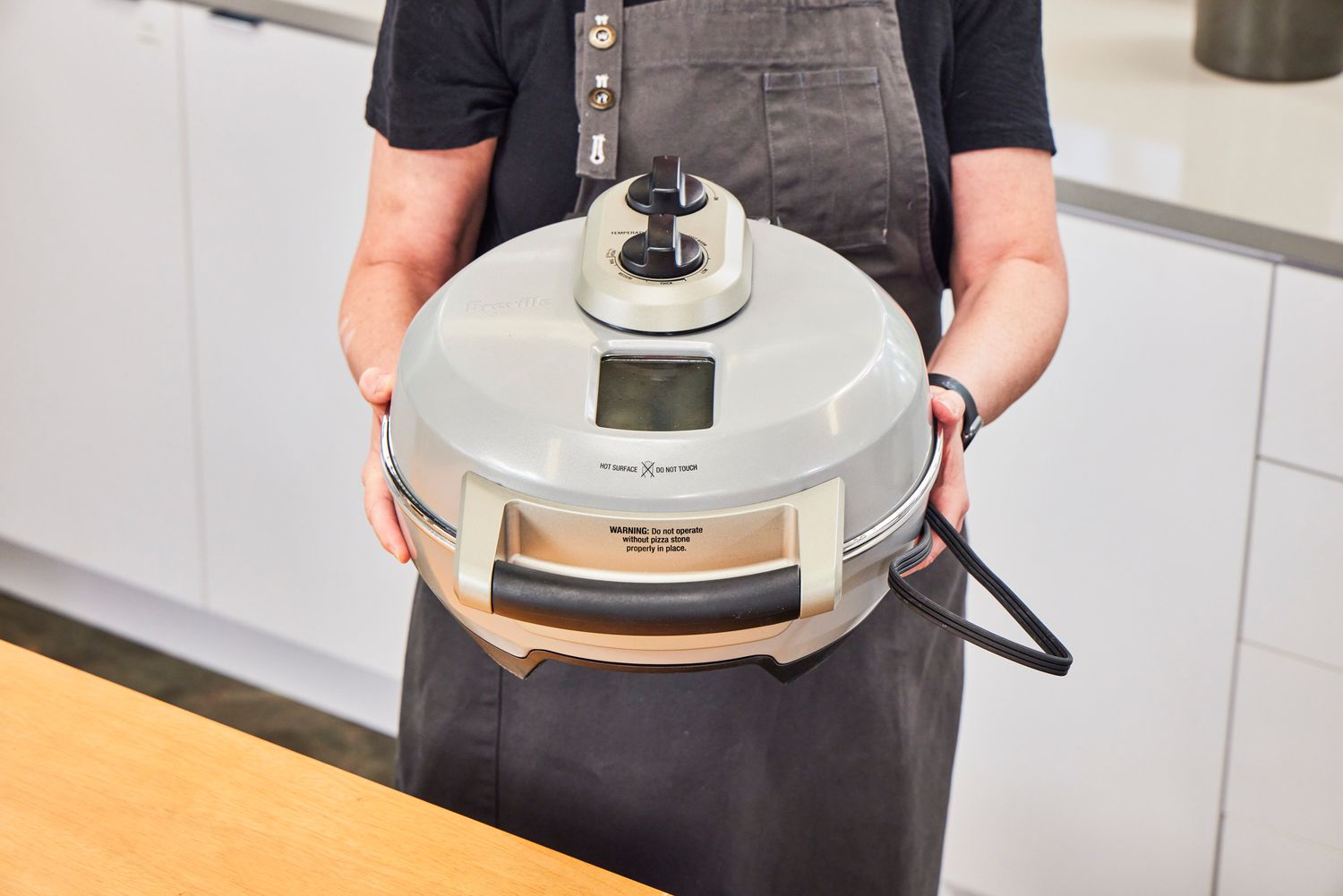 A person holding the Breville pizza maker.