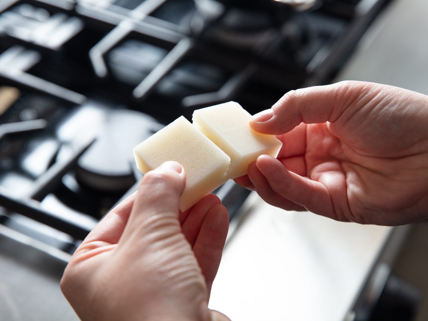 Breaking two pieces of white mochi along its scored lines for ozoni soup.