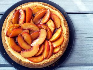 Overhead view of a Bourbon-Roasted Peach Cheesecake, set on a wooden surface.