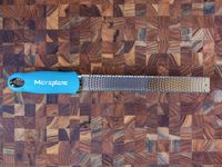 blue-handled microplane grater on a wooden surface