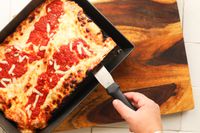 Deep dish pizza being served out of the LloydPans Kitchenware Detroit Style deep dish pizza pan