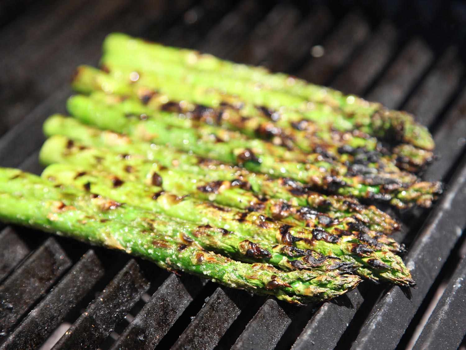 Asparagus getting nicely charred on a grill.