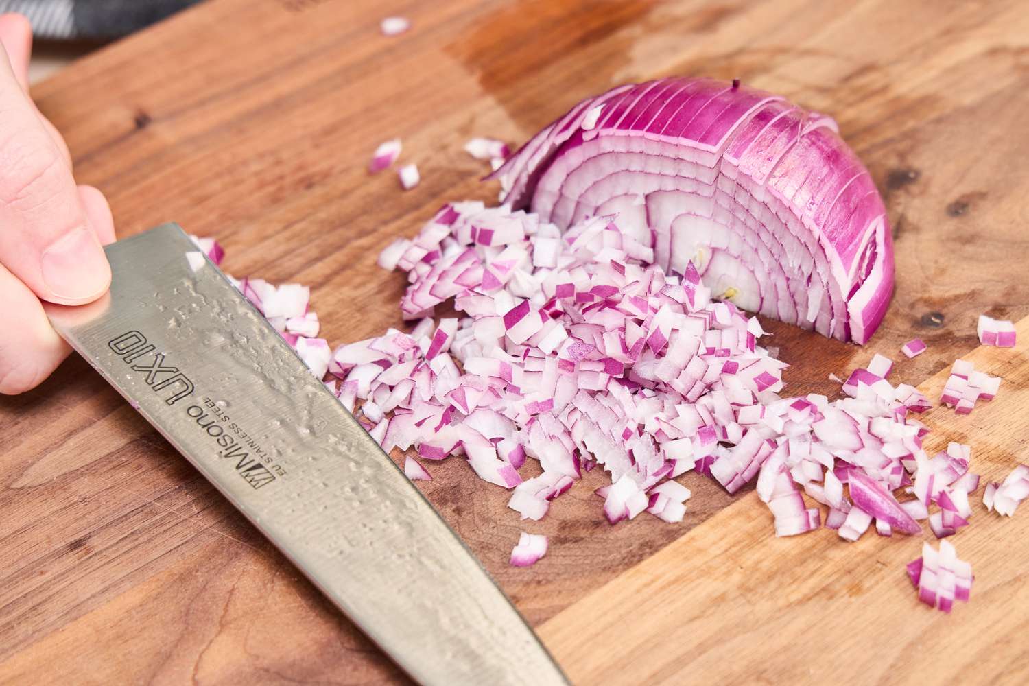 A pile of diced onion beside the Misono UX10 Chef’s Knife No. 712