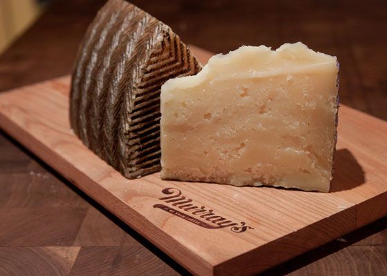 Wedges of manchego cheese, showing the dry, crumbly inside and the patterned, waxed outside on a wooden board.