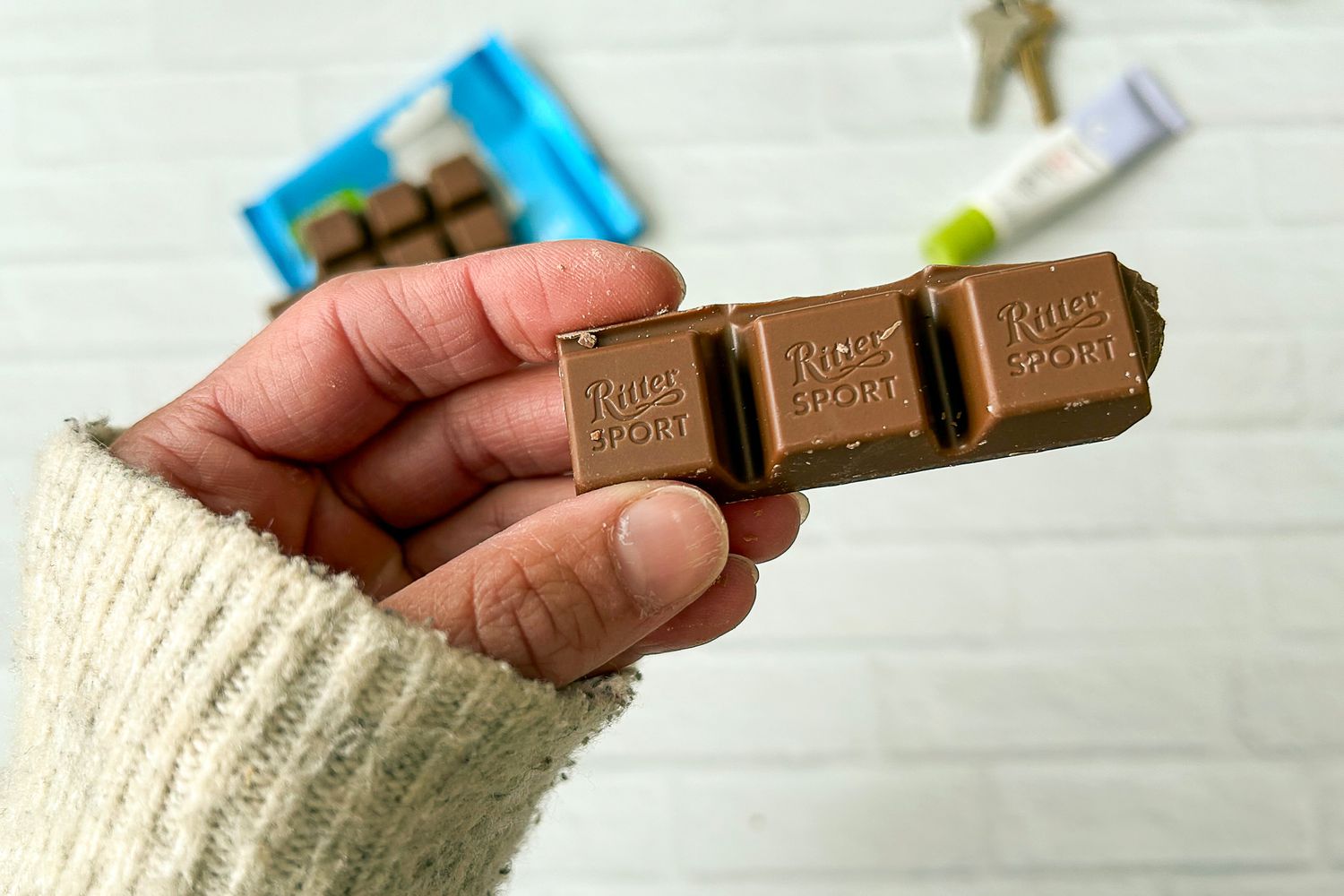 A hand holding pieces of Ritter Sport Alpine Milk Chocolate