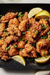 Fried Japanese chicken on a black plate with chopsticks, lemon, and a stylish napkin