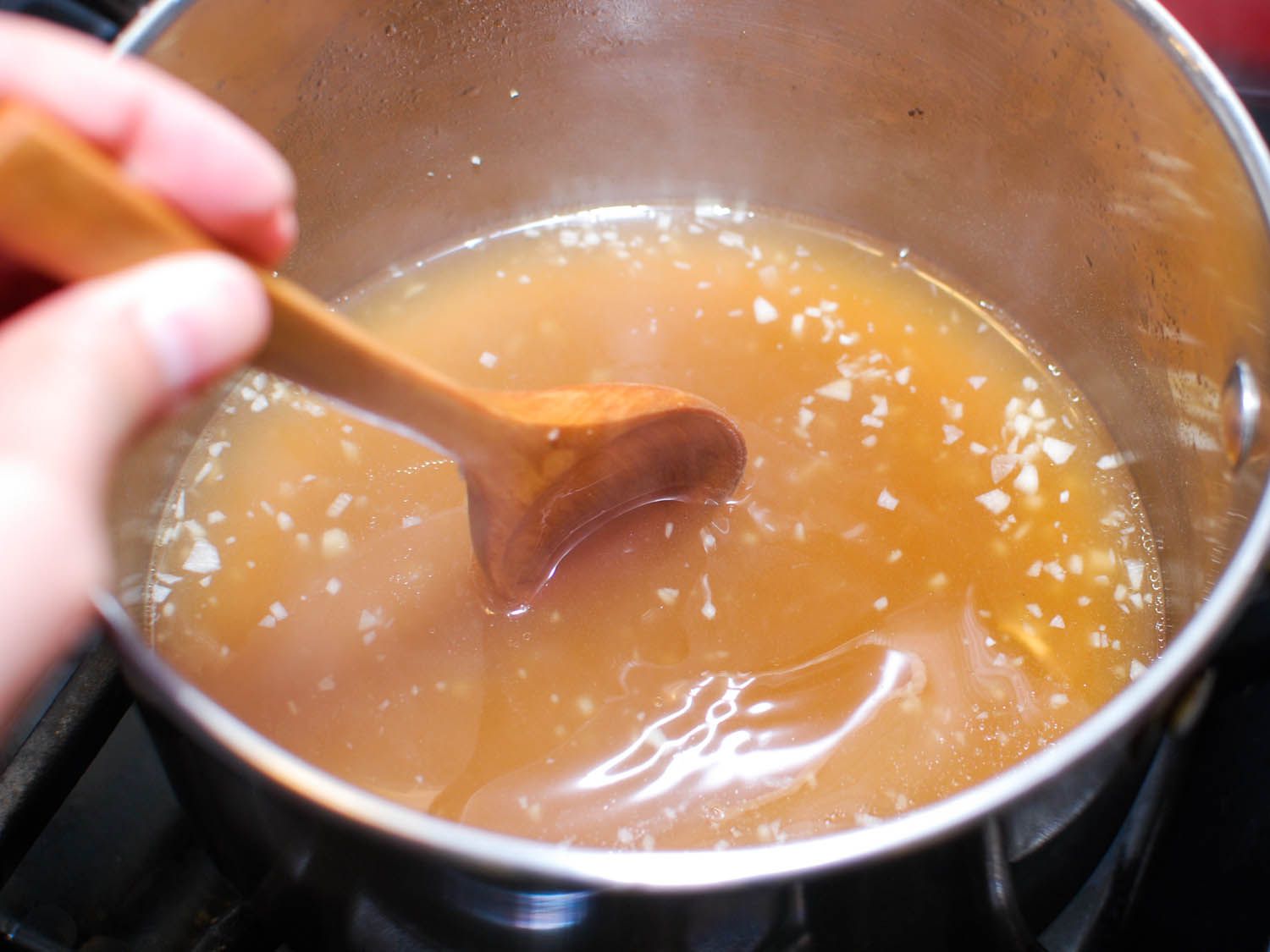 The cornstarch is vigorously stirred into the chicken stock.
