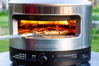 Pizza being cooked in a Solo Stove Pi Prime pizza oven with flames inside