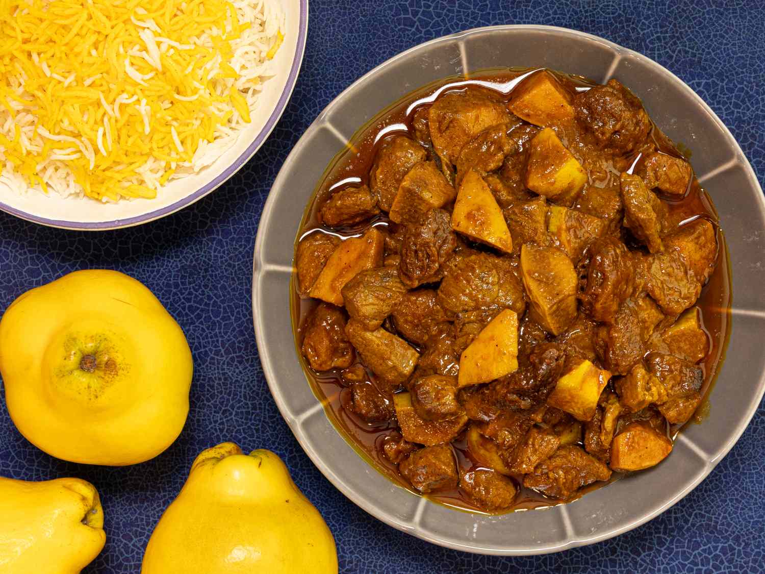 A bowl of Khoreshebeh a Persian stew made with quince and meat next to a plate of rice and fresh quinces