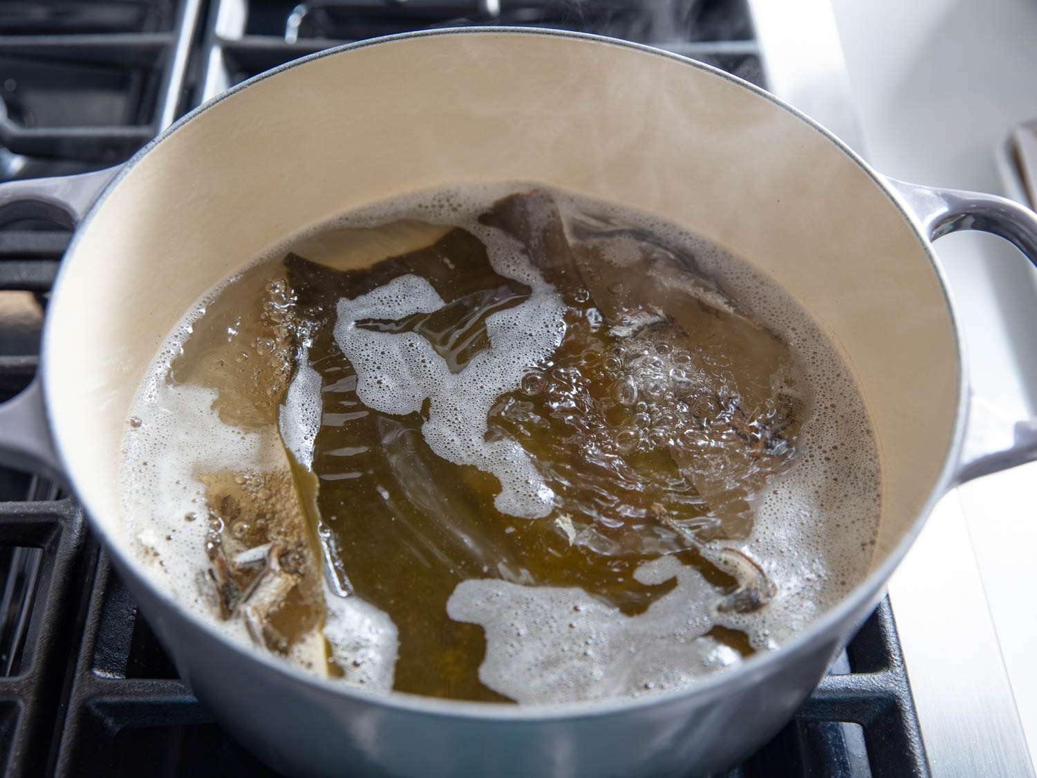 Combining dried anchovies, herring, and seaweed with water and simmering in a Dutch oven.