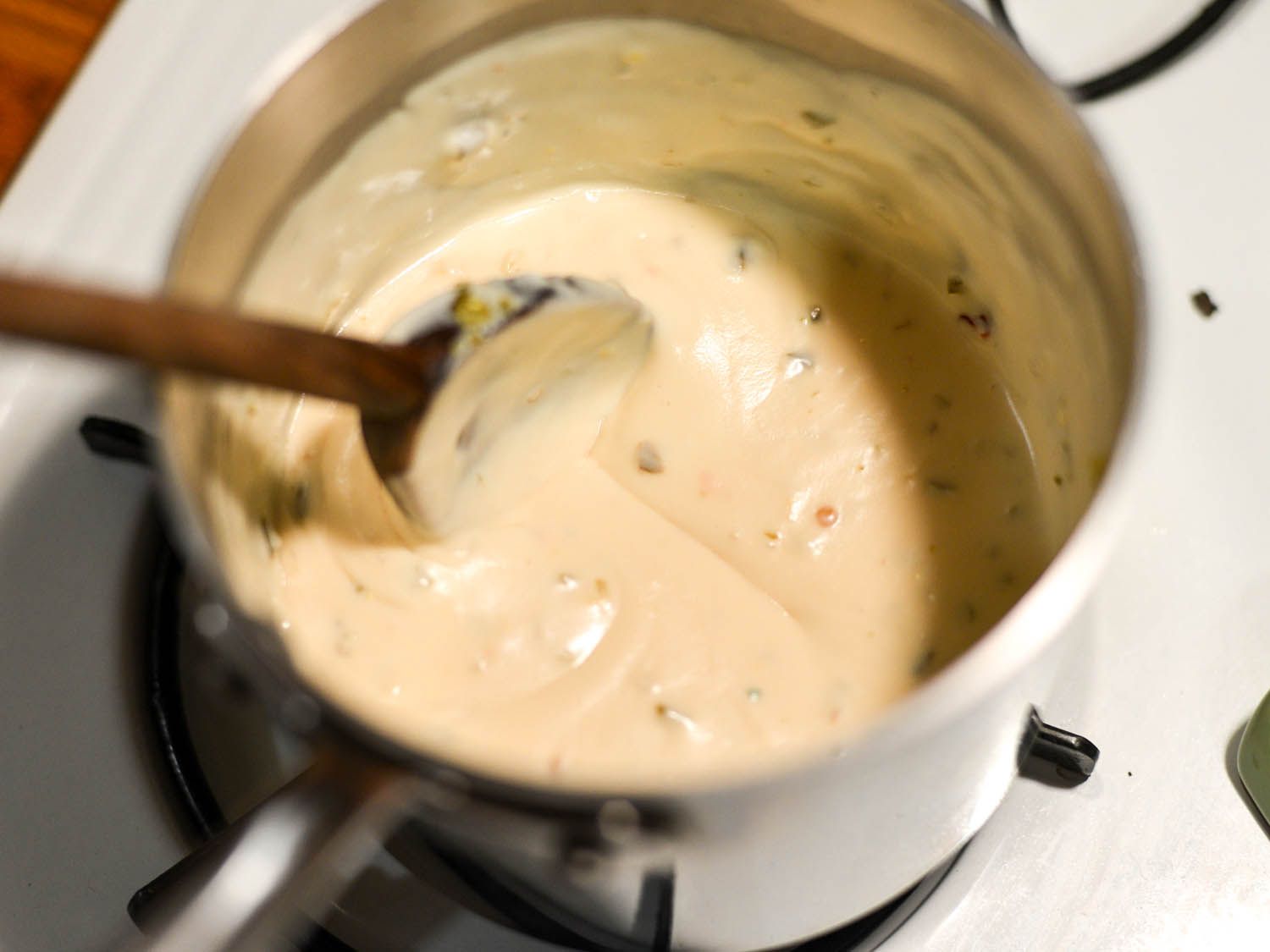 Stirring a pot of pepper cheese sauce with wooden spoon