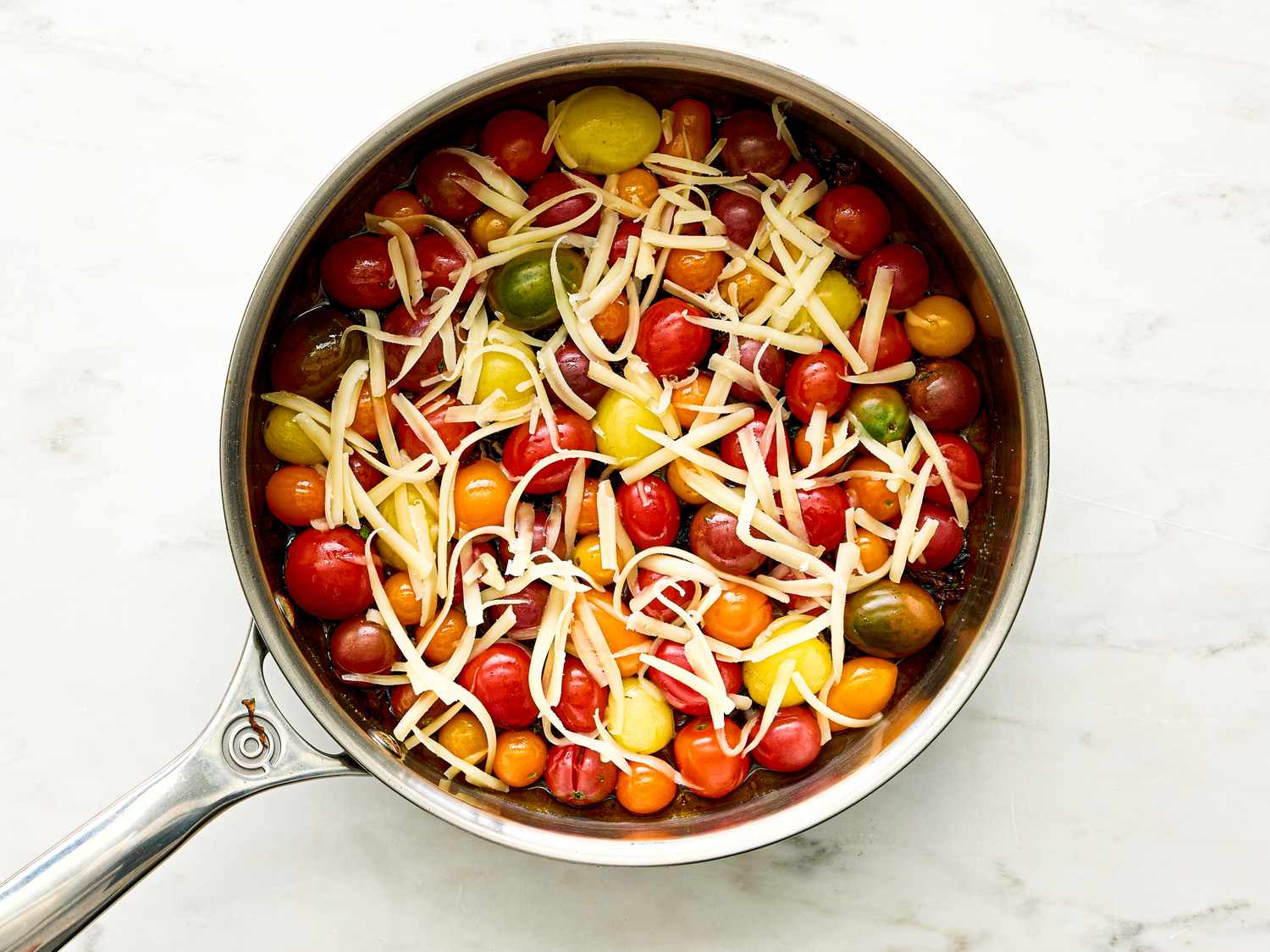 Skillet filled with cherry tomatoes topped with shredded cheese