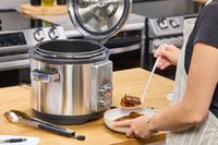A person examines food cooked in the Breville the Fast Slow Pro
