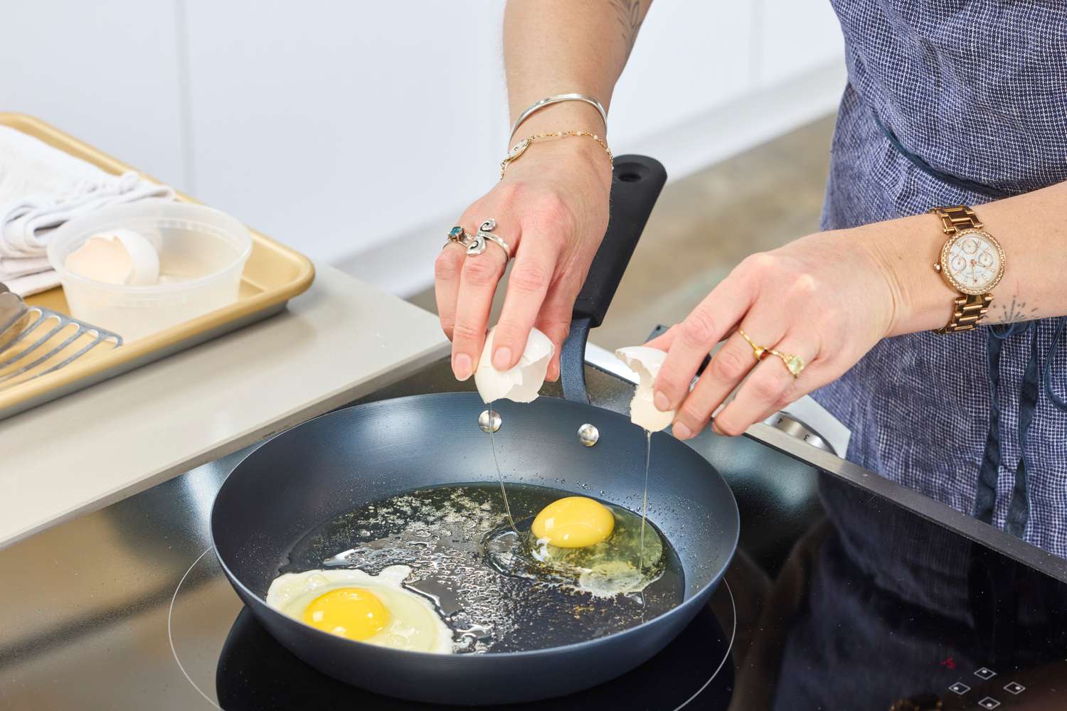 A person cracks eggs into the OXO Obsidian Pre-Seasoned Carbon STeel Pan