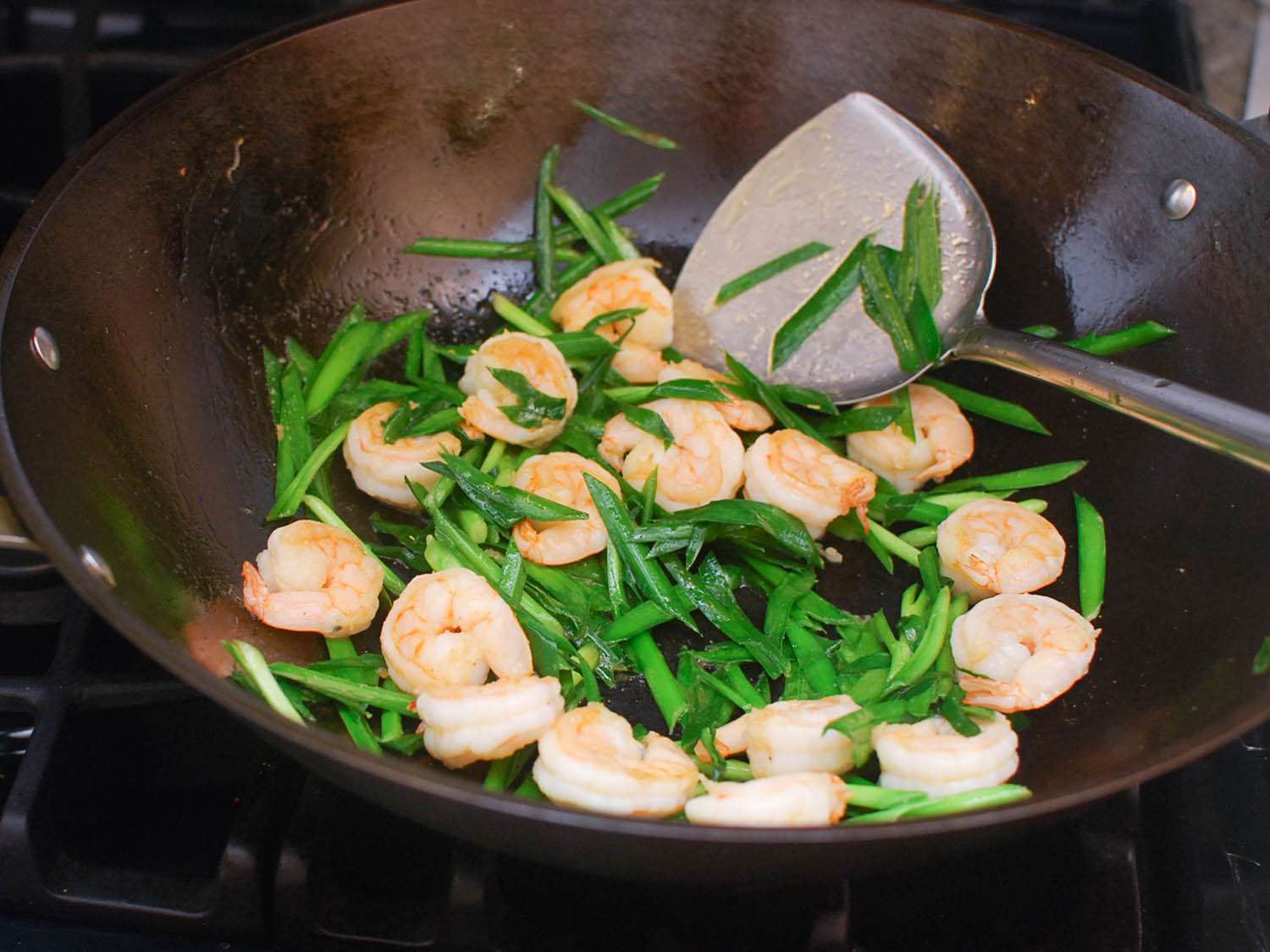 The shrimp and chives continue to cook in the wok.