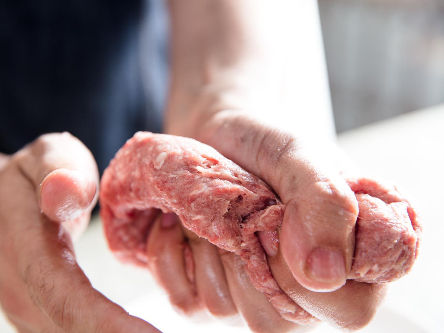 A hand squeezing a ground beef mixture 