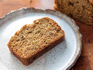 A slice of freshly baked zucchini bread, served on a ceramic plate with an irregular rim.