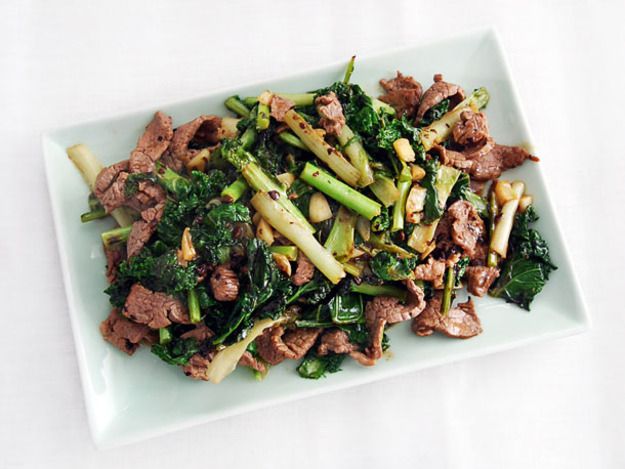 Overhead view of stir-fried beef with kale and frisée in black bean sauce, served on a rectangular porcelain platter.