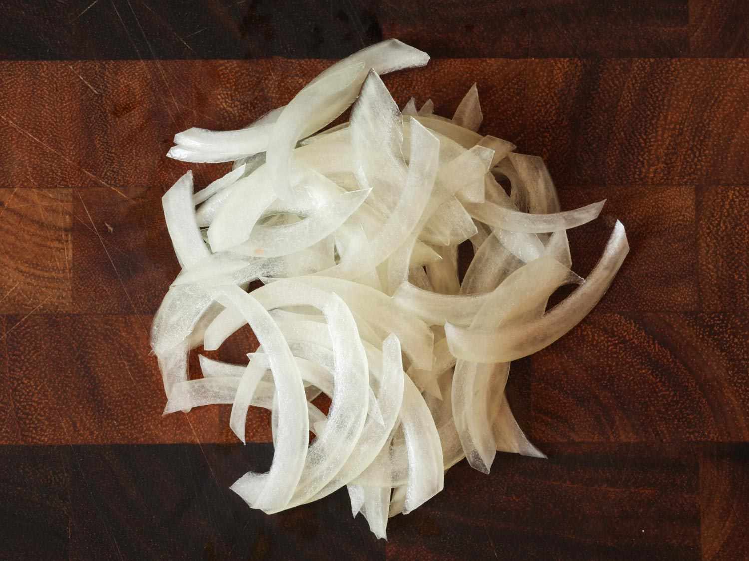 A pile of raw onion that has been sliced from pole to pole.