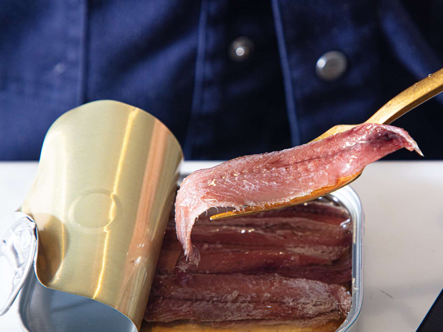 Canned anchovies being lifted with a utensil