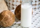 Side view of coconut milk surrounded by coconuts