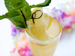 A Fog Cutter cocktail in a Collins glass garnished with a wedge of lemon and a sprig of mint.