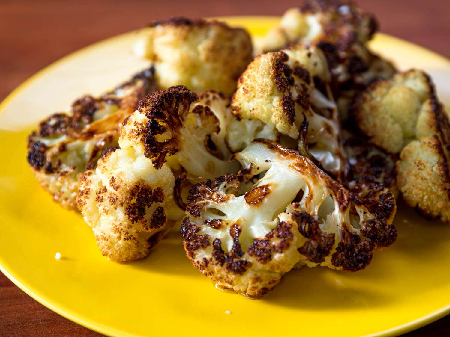 Close-up of roasted, deeply browned wedges of cauliflower.