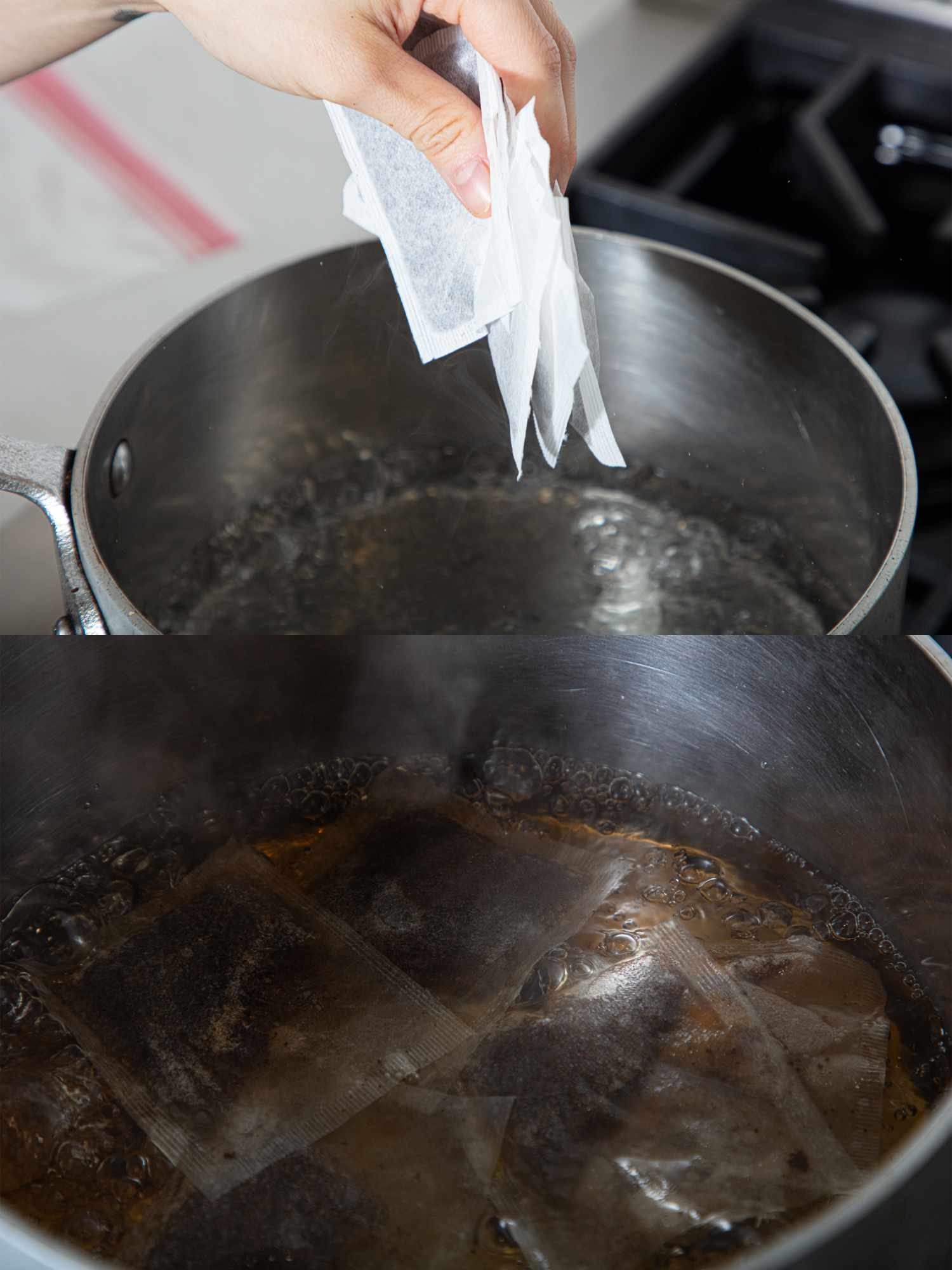 A hand placing teabags into boiling water in a pot on a stovetop