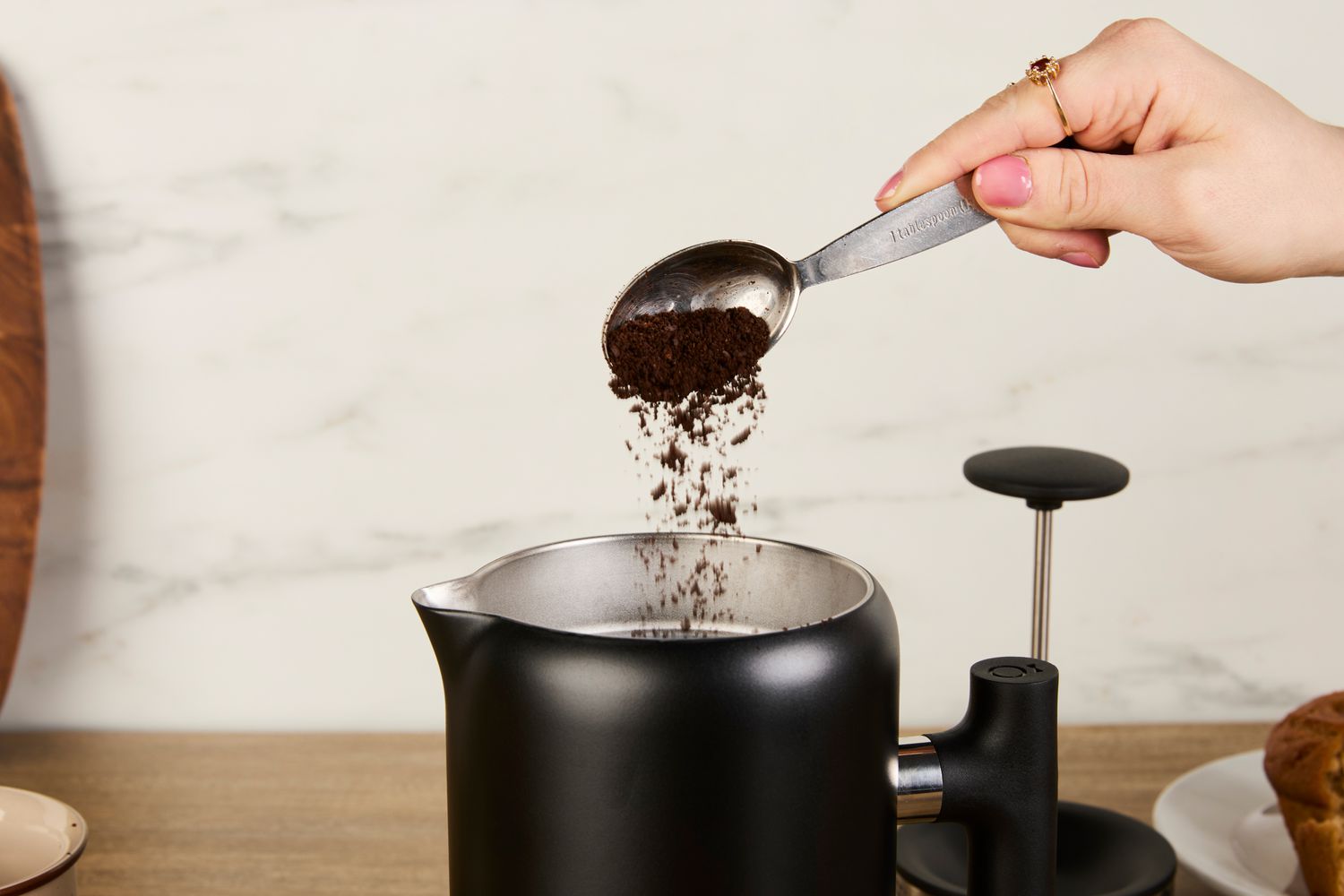 A person adding coffee grounds to the Fellow gooseneck kettle.
