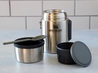 the pieces of the stanley all in one food jar on a blue surface with tile backdrop