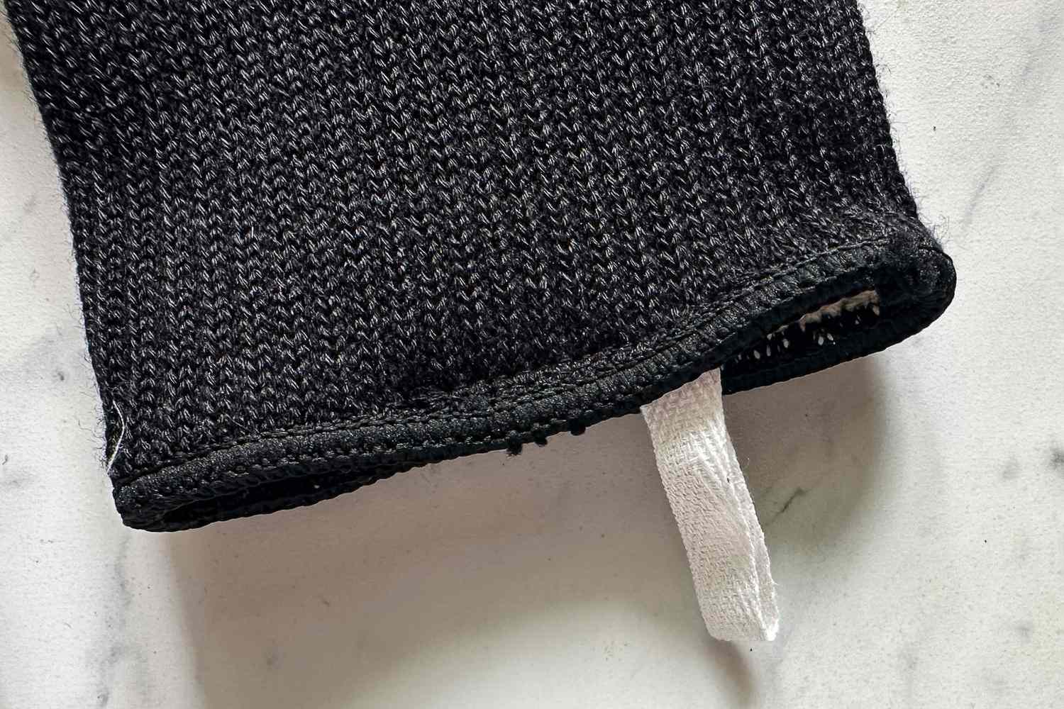 Closeup of a knitted fabric sleeve with a white loop at the edge on a light surface
