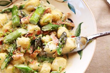A plate of homemade ricotta asparagus with fresh asparagus, prosciutto, and Parmigiano-Reggiano.