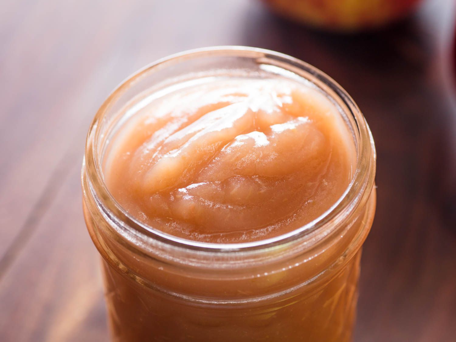 Close-up of an open glass jar of homemade applesauce.