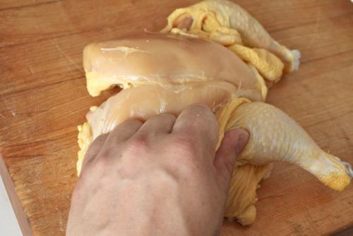 Author removing skin from the breast of a butterflied chicken.