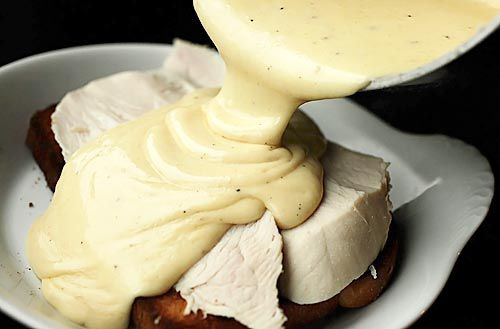 Pouring Mornay sauce on top of roast turkey and a slice of toast. 