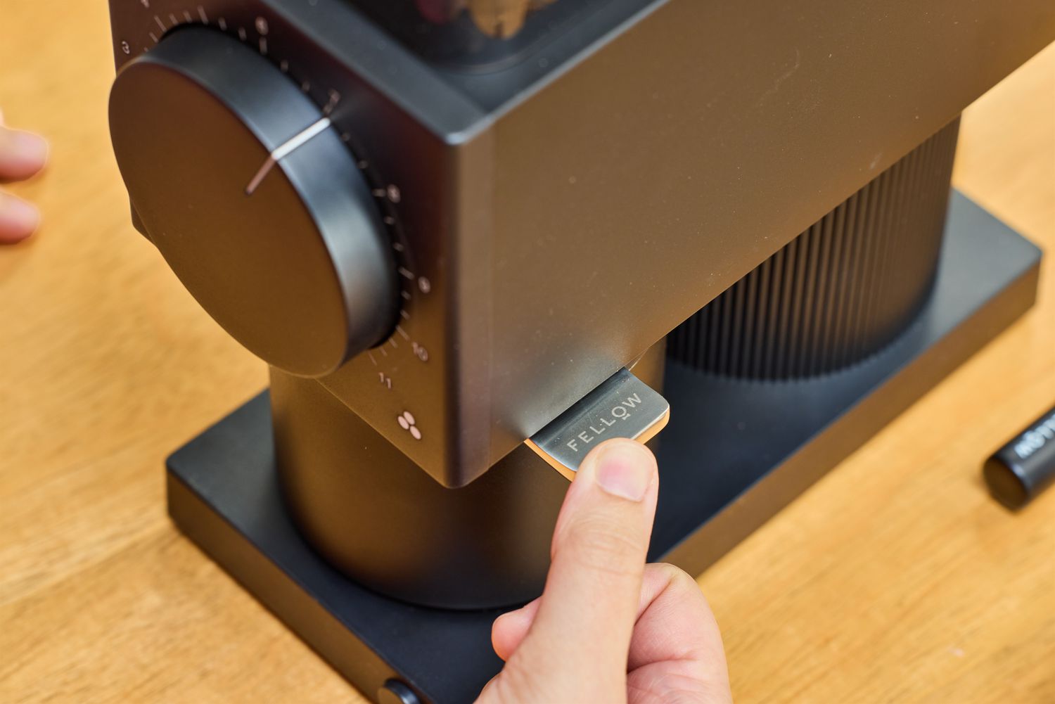 A person presses a button on the Fellow Ode Gen 2 Coffee Grinder