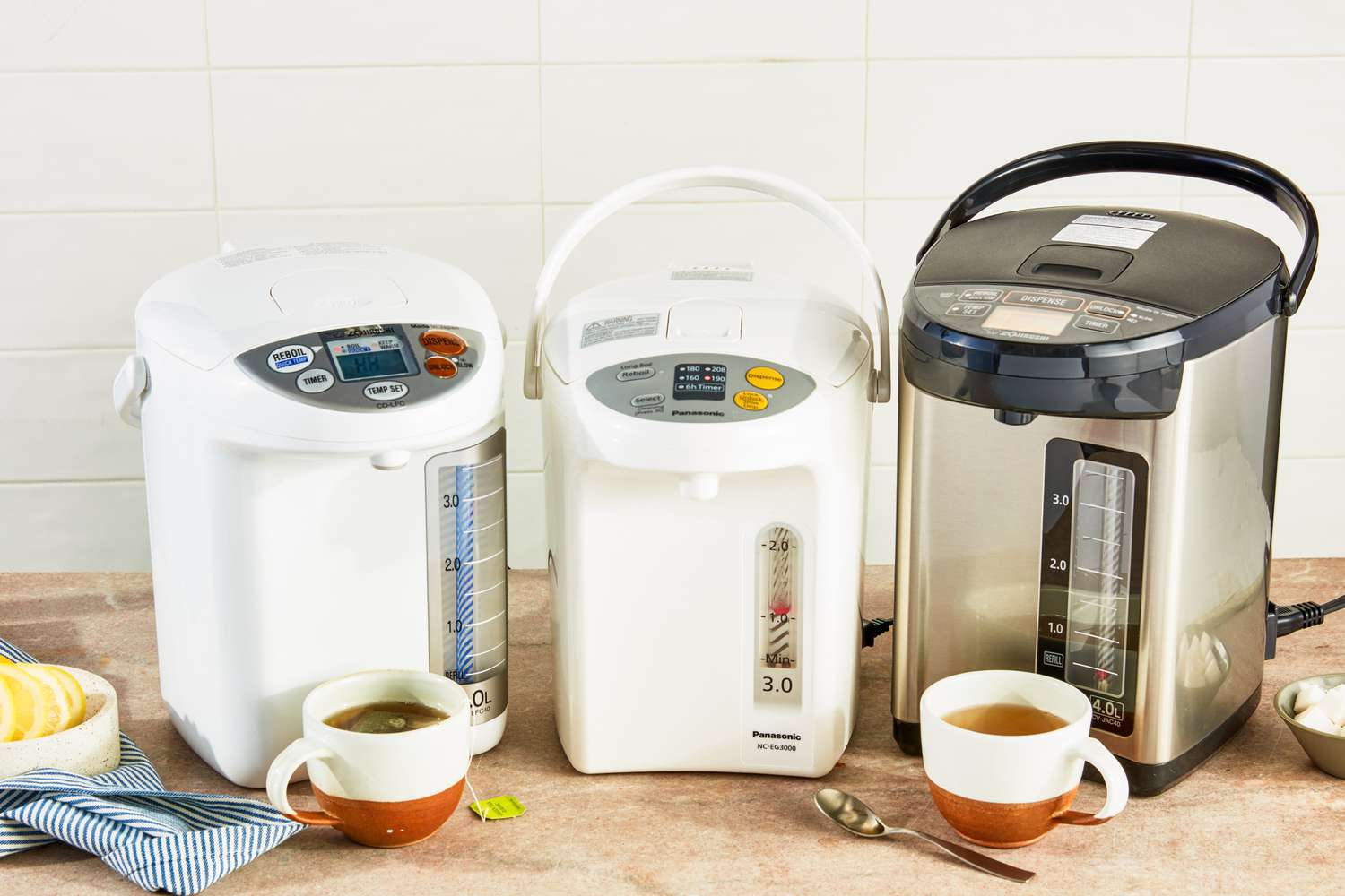 Three hot water dispensers on a wooden countertop.