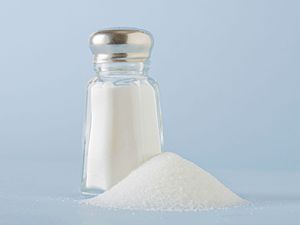 A salt shaker next to a small pile of salt