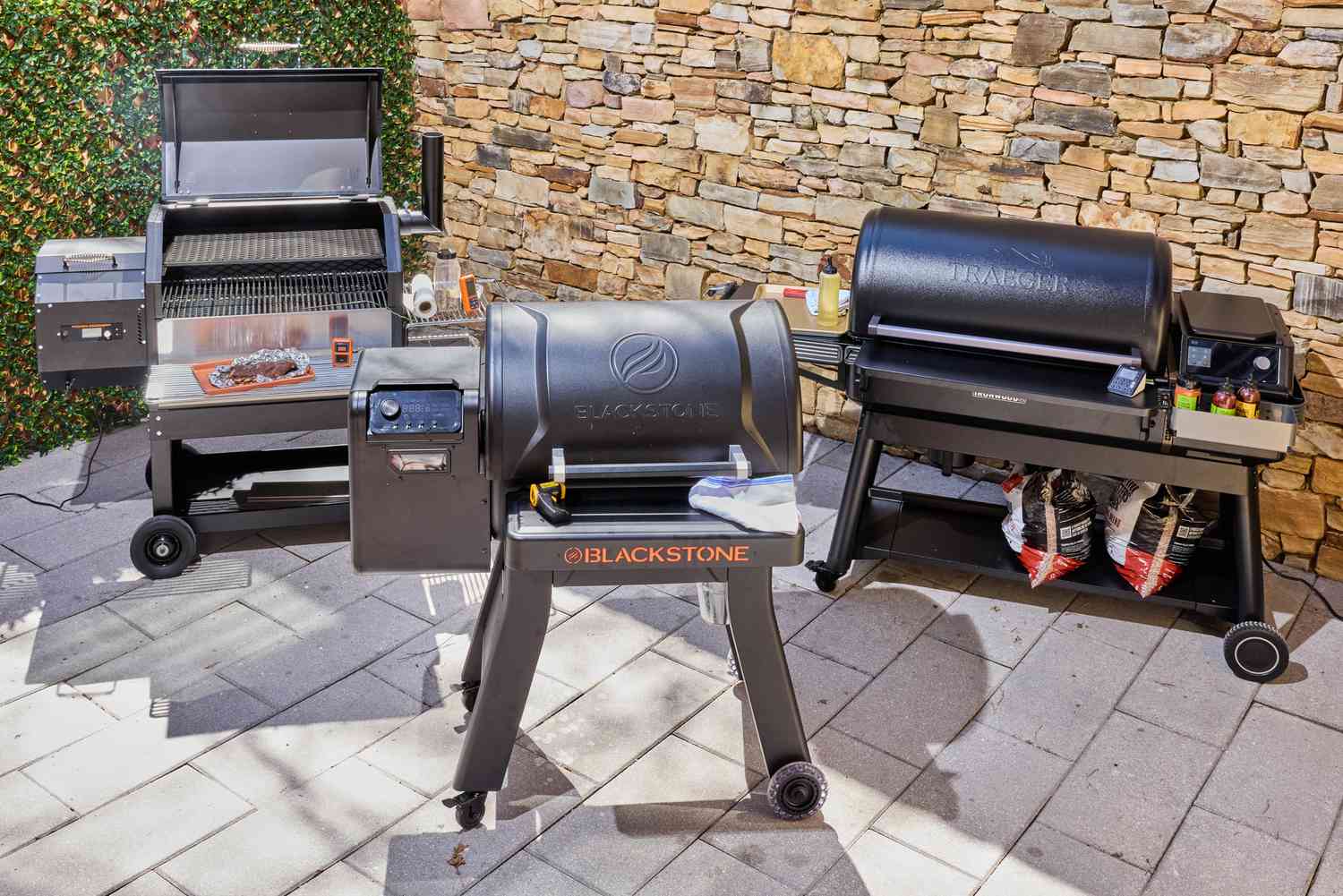 Three pellet grills on an outdoor patio.