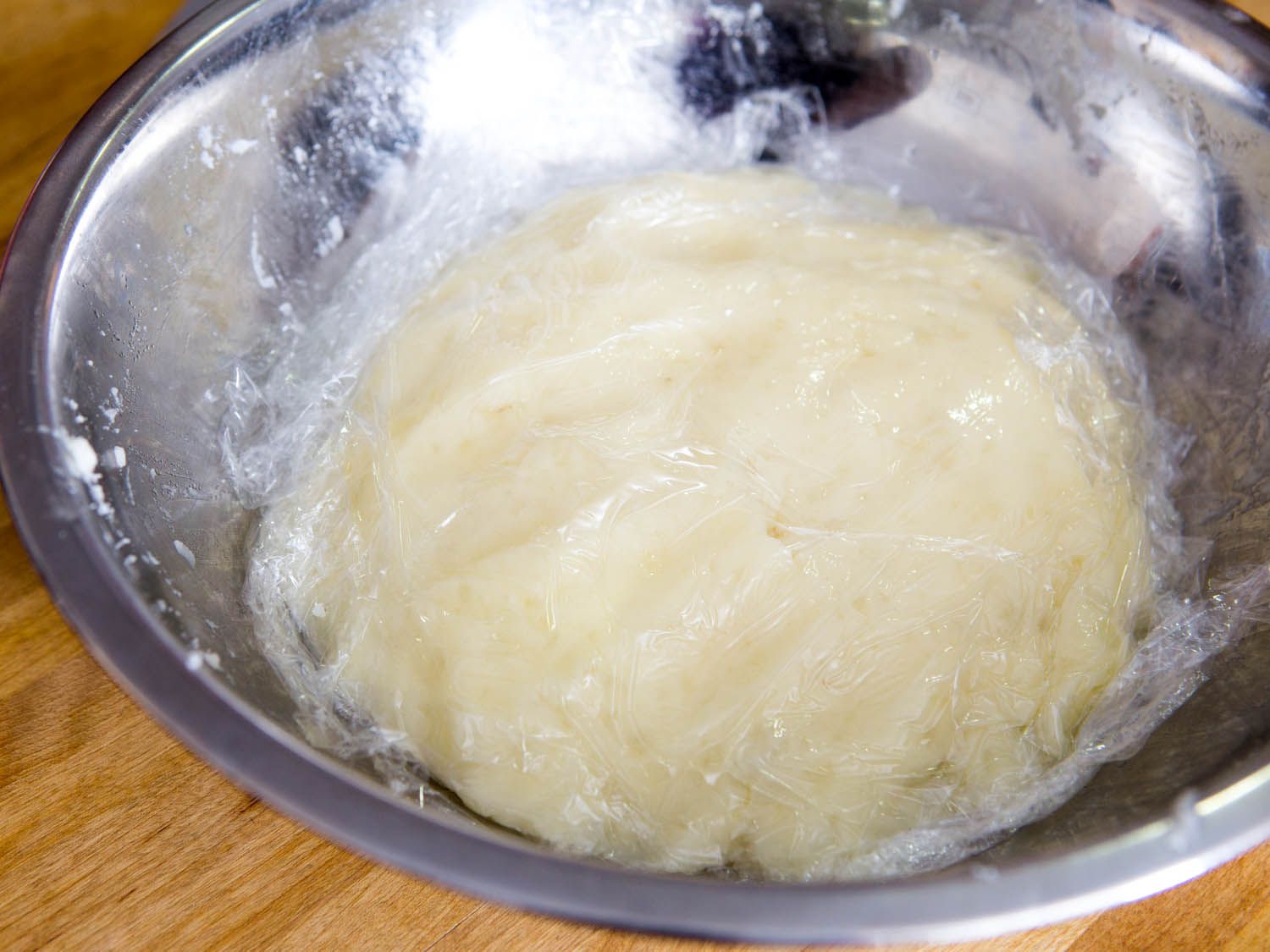 Mashed potatoes in a bowl covered with plastic wrap.
