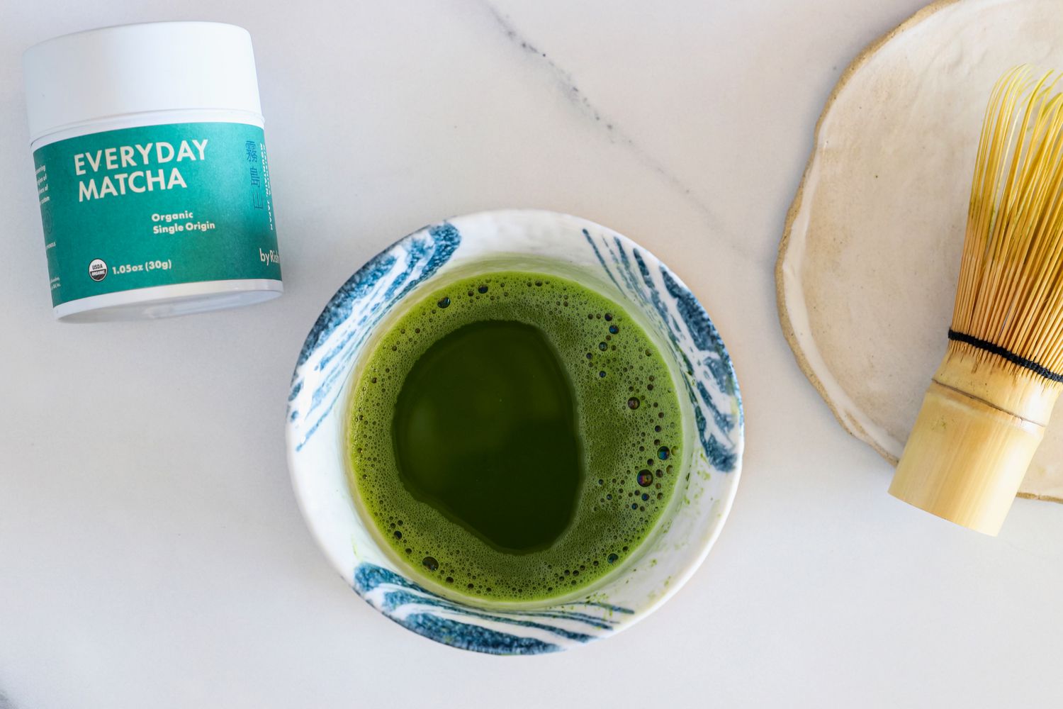 A glass of Rishi Tea Everyday Matcha next to the container