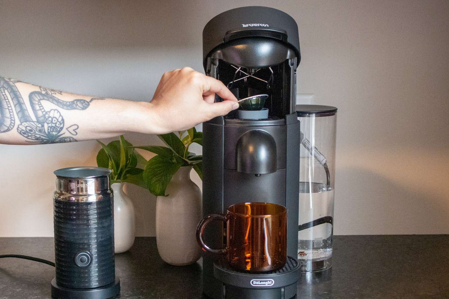 A hand loading a pod into a Nespresso machine