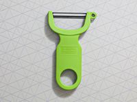 A green vegetable peeler on a grey surface