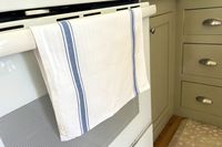 Kitchen oven door with a white towel featuring blue stripes draped over the handle
