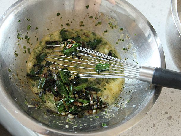 Sautéed ramps are added to the bowl of beaten egg yolk.